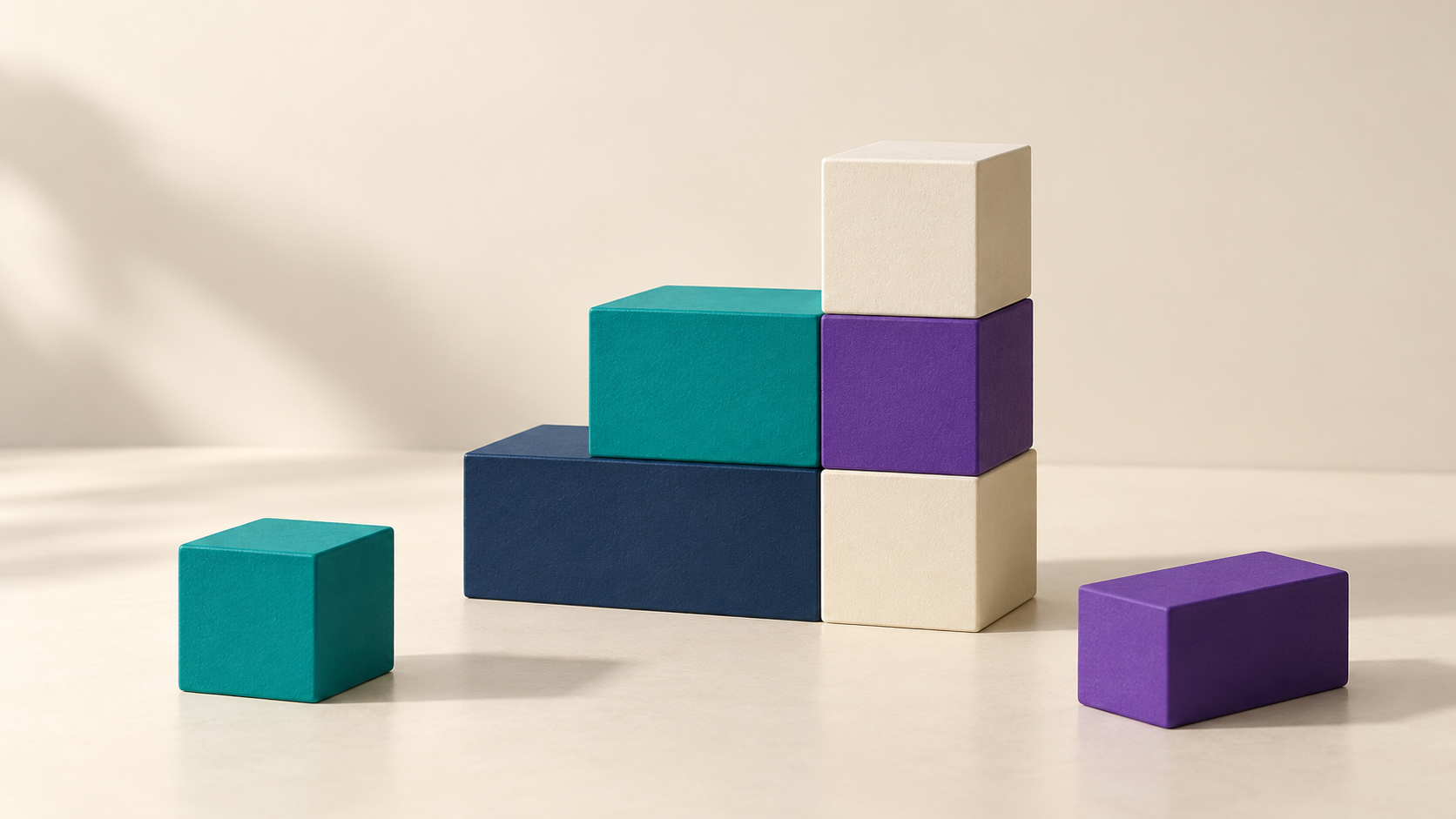 Navy, teal, purple and ivory building blocks arranged in a stepped structure, with two loose blocks beside it.